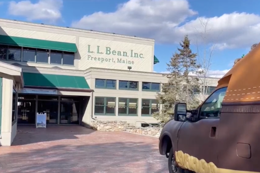 An image of an L.L. Bean storefront with a vehicle approaching it.