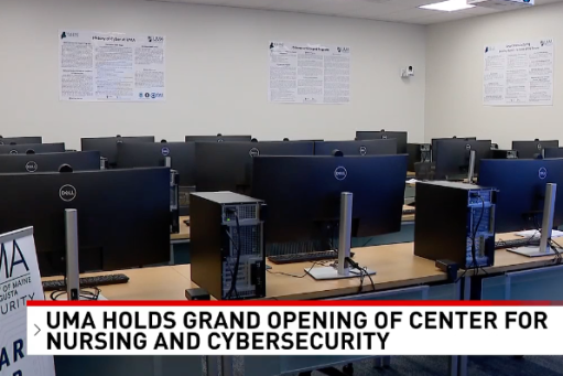 A room of computers with a news banner announcing a new cybersecurity center