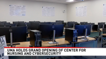 A room of computers with a news banner announcing a new cybersecurity center